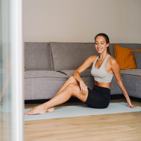 Person smiling while stretching gently on a yoga mat at home.